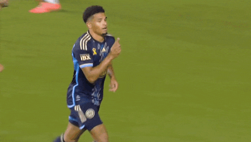 a soccer player wearing blue shorts and pink shoes is running on a field