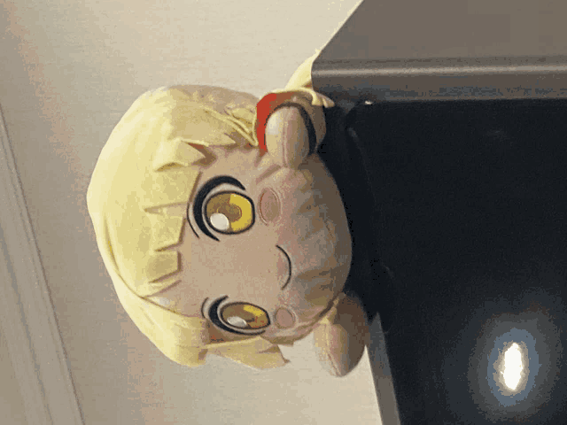 a stuffed doll with a yellow hair and yellow eyes is hanging upside down
