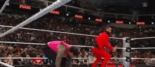 a wrestler in a red outfit is standing in a ring