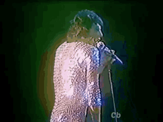 a person singing into a microphone with cb written on the bottom right