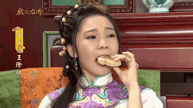 a woman in a purple and white dress is eating a piece of food