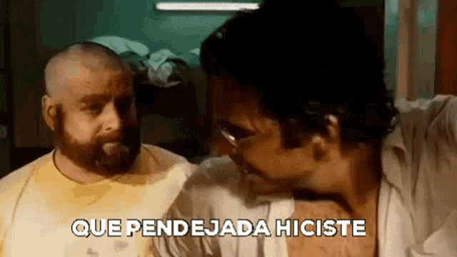 two men are standing next to each other in a room and one of them is talking in spanish .