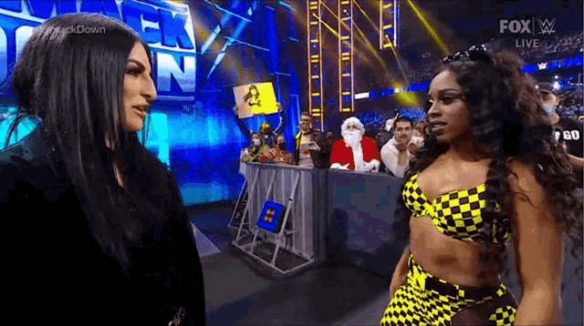 two women are standing next to each other in a wrestling ring talking to each other .