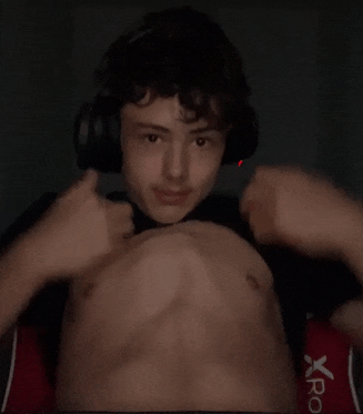 a young man wearing headphones is flexing his muscles while sitting in a chair .