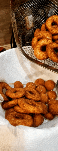 a basket of fried donuts sits on a paper towel next to a basket of chicken nuggets