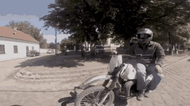 a man wearing a helmet is riding a dirt bike on a brick road