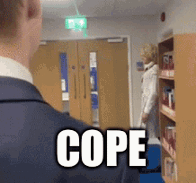 a man in a suit is standing in a hallway with the word cope on his shoulder