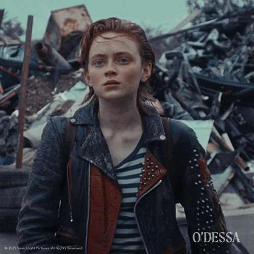 a woman in a leather jacket is standing in front of a pile of scrap metal with the words odessa on the bottom