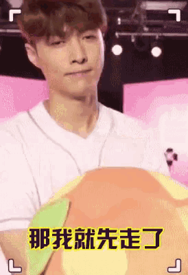 a man in a white shirt is holding a colorful pillow and making a funny face .
