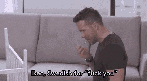a man is sitting on a couch smoking a cigarette and talking on his phone .