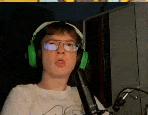 a young man wearing headphones and glasses is talking into a microphone .