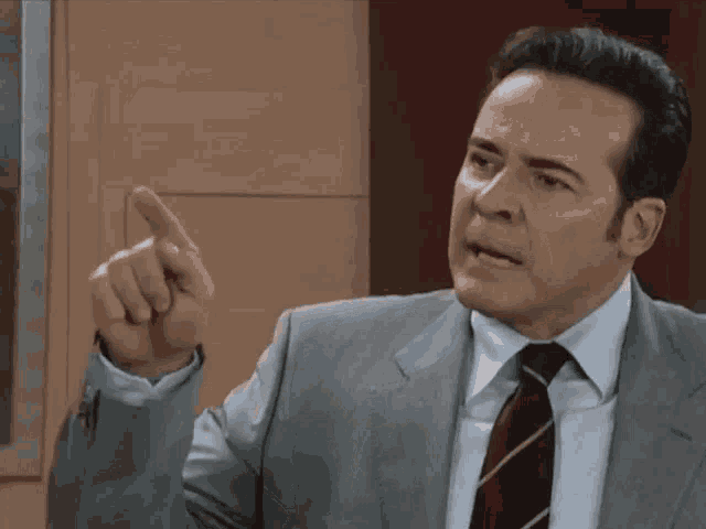 a man in a suit and tie is pointing with his finger