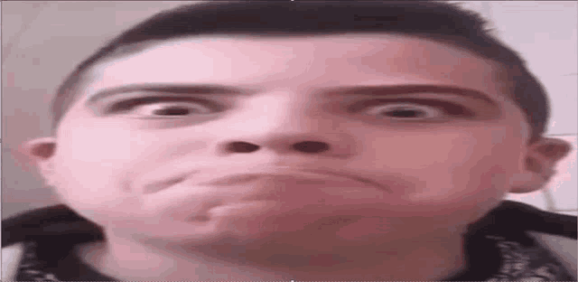 a young man is making a funny face with his mouth open and his eyes wide open .