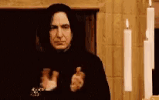 a man in a black robe is standing in front of a candle holder .