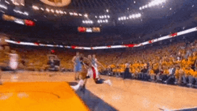 a basketball game is being played in a stadium with a crowd of people watching .