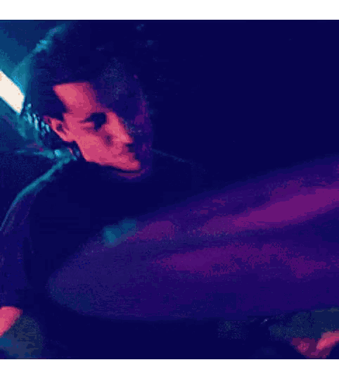 a man in a black shirt is playing drums in a dark room .