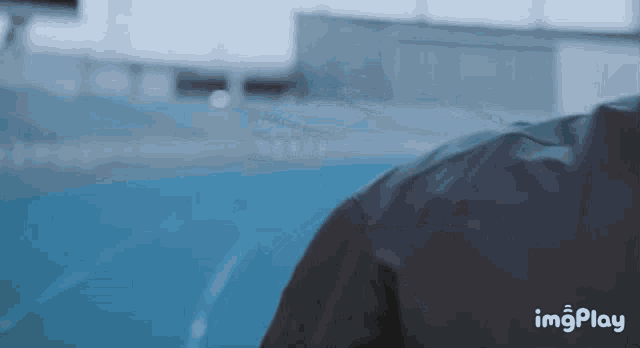 a person in a black jacket is walking on a track with imgplay written in the corner