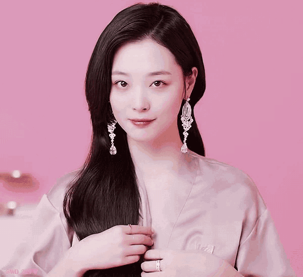 a woman wearing a pink robe and earrings with the letters snr on the bottom