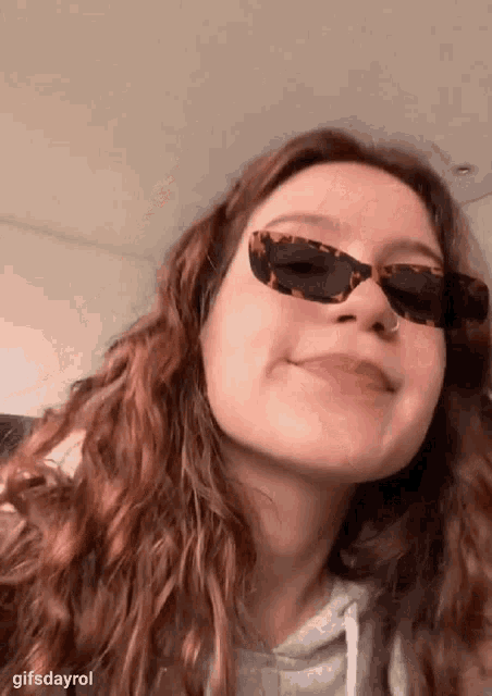 a woman wearing sunglasses and a nose ring is making a face .