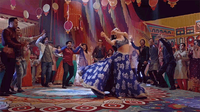 a group of people are dancing on a stage with a woman in a blue dress