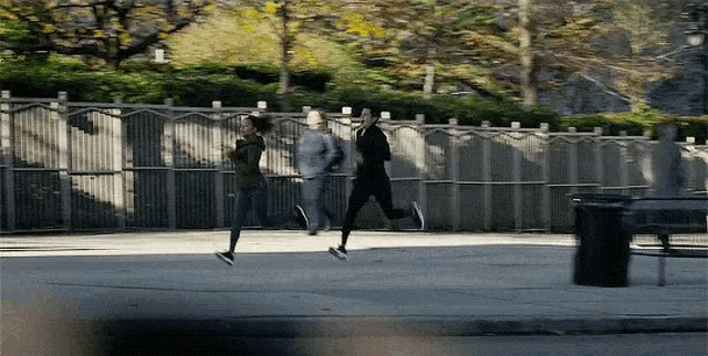 a group of people are running on a sidewalk in a park