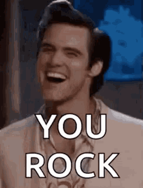 a man is laughing and saying `` you rock '' while wearing a suit .