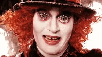 the mad hatter from alice in wonderland is wearing a red wig and hat .