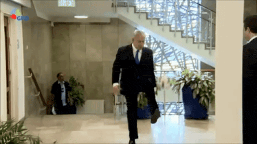 a man in a suit and tie is standing in a hallway with a sign that says gpd