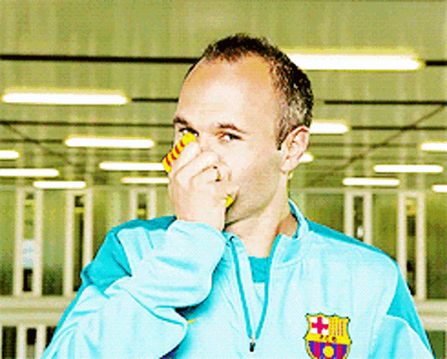a man wearing a barcelona jacket covering his nose