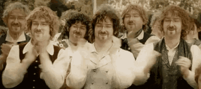 a group of men standing next to each other clapping their hands .