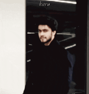 a man with a beard is standing in a doorway with the name karu on the bottom