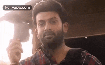 a man in a plaid shirt is holding a camera in his hand .
