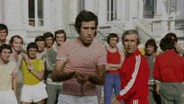 a man in a red and white striped shirt stands in front of a group of people