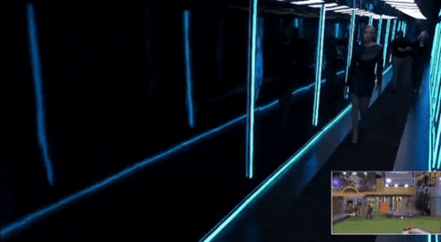 a woman stands in a dark hallway with blue lights on the walls