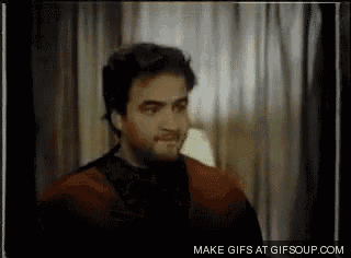 a man with a beard is standing in front of a window in a room with a lamp .