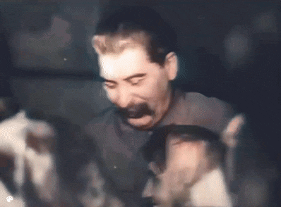 a man with a mustache is standing in a dark room with a group of people .