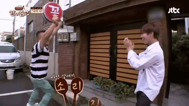 two men are standing in front of a building with a sign that says jtbc on it