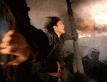a man is holding a torch in front of a burning building