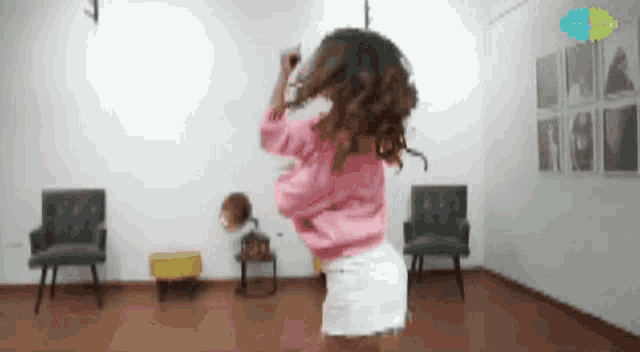 a woman in a pink top and white shorts is dancing in a room