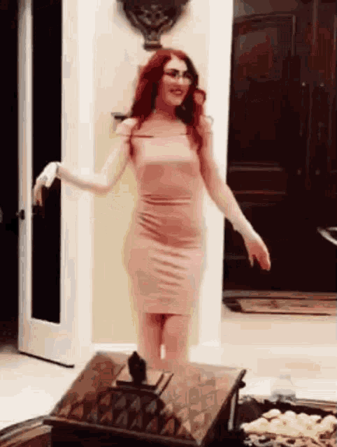 a woman in a pink dress is standing in a living room