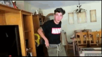 a man wearing a marvel t-shirt is dancing in a living room