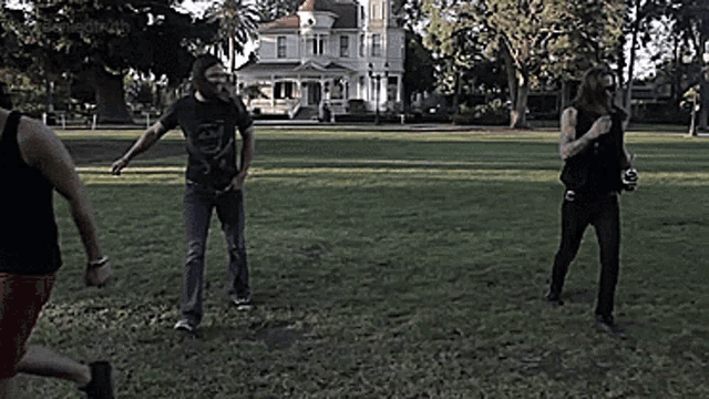 a man in a black tank top stands in a field with two other men