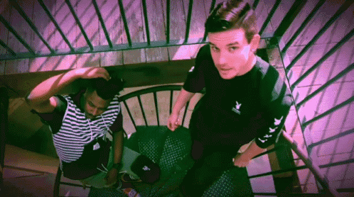 two men are standing on a set of stairs with one wearing a black shirt that says playboy