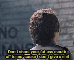 a man is standing in front of a brick wall and says " don 't shoot your fat-ass mouth off to me "