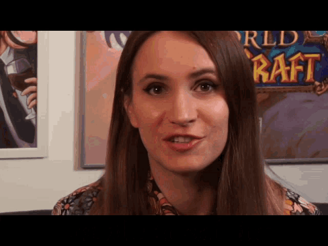 a woman is standing in front of a poster that says world of warcraft