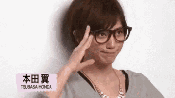 a young man wearing glasses and a necklace is making a face .