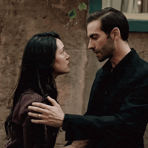 a man and a woman are looking at each other and the man has a wedding ring on his finger