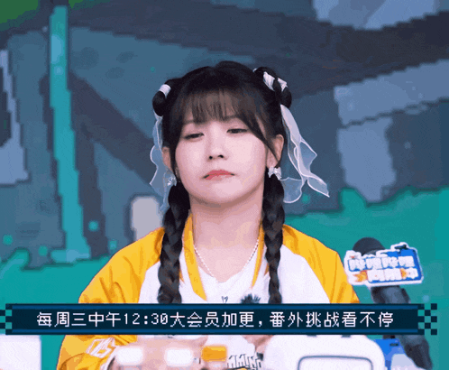 a girl sitting in front of a microphone with chinese writing on the screen