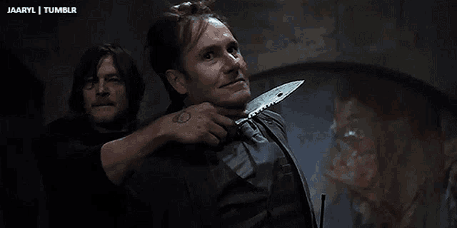 a man is holding a knife to another man 's neck .