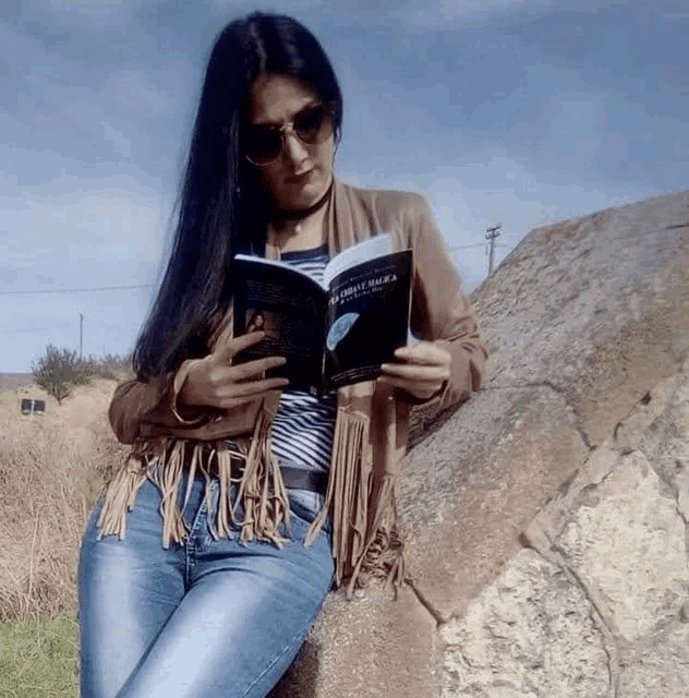 a woman is leaning against a rock reading a book titled " la divina sencia "